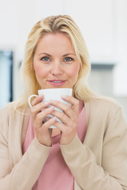 Bela jovem com xícara de café na cozinha