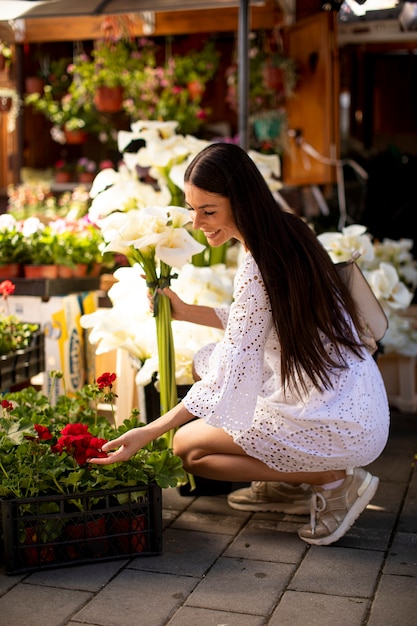 Bela jovem comprando flores no mercado de flores