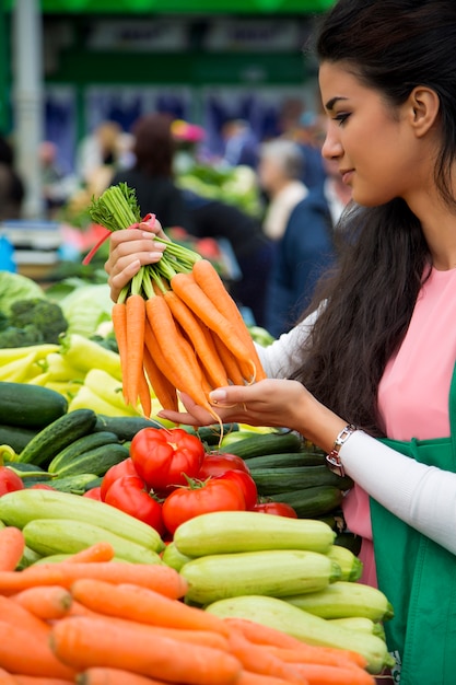 Bela jovem comprando legumes no mercado