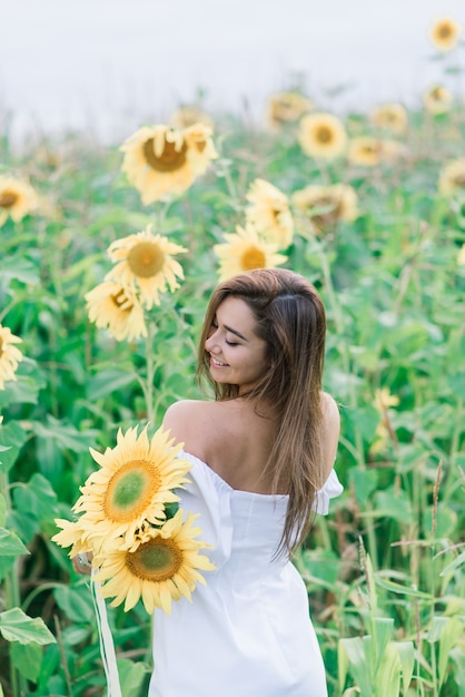 Bela jovem curtindo a natureza no campo de girassóis ao pôr do sol