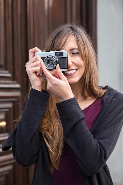 Bela jovem de pé fotografando com a câmera