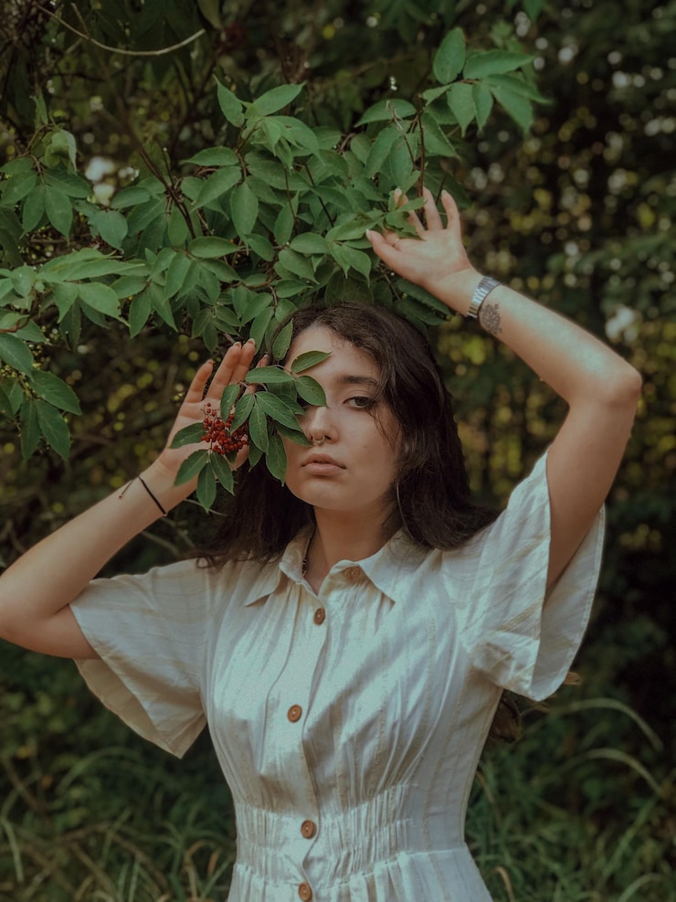 Foto bela jovem de pé junto às plantas no campo