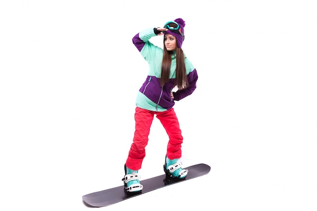 bela jovem de terno de esqui roxo monta snowboard preto