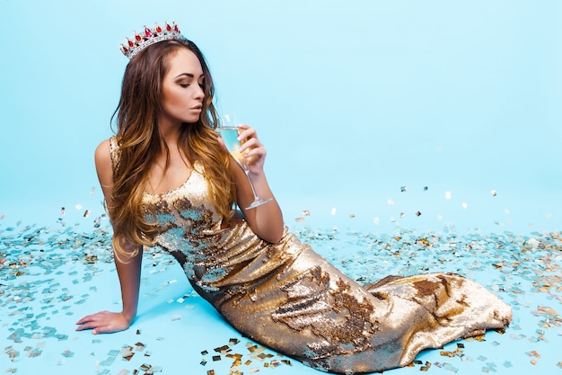 Bela jovem de vestido dourado com champanhe