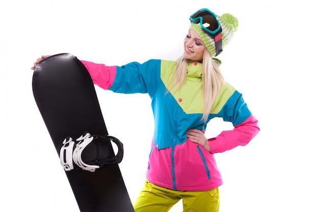 Bela jovem em roupa de esqui e óculos de esqui segurar snowboard