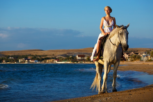 Bela jovem em um cavalo perto do mar