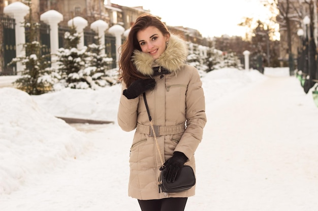 Bela jovem em um parque de inverno congelado com neve no inverno