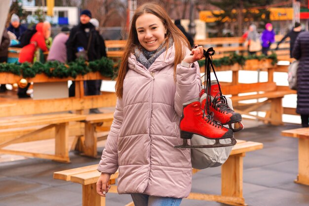 Bela jovem em uma pista de patinação com patins nas mãos