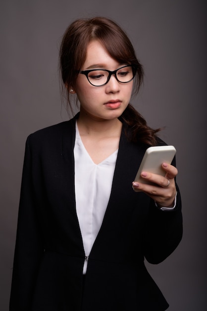 Bela jovem empresária asiática usando telefone celular