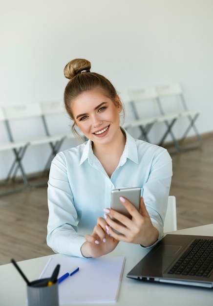 Bela jovem empresária sorridente trabalha no escritório moderno com um laptop. Conceito de sucesso. Conferência online