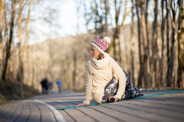 Foto bela jovem fazendo hatha yoga e meditando na calçada no parque da cidade