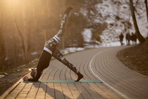 Foto bela jovem fazendo hatha yoga e meditando na calçada no parque da cidade