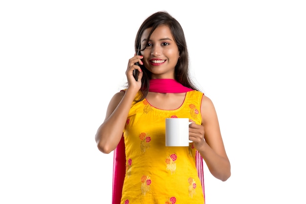Bela jovem ligando para um dispositivo smartphone enquanto bebe uma bebida saborosa de café ou chá
