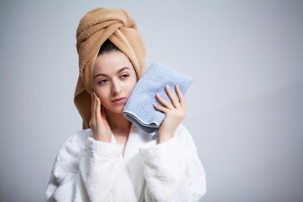 Bela jovem limpa a toalha de rosto depois de tomar banho.