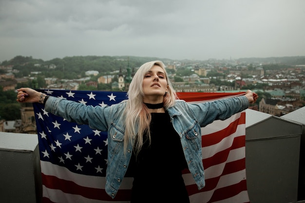 Bela jovem loira em um espaço da cidade com a bandeira americana