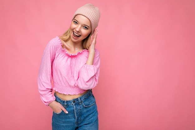 Bela jovem loira feliz, positiva, isolada sobre a parede de fundo colorido, usando roupas casuais