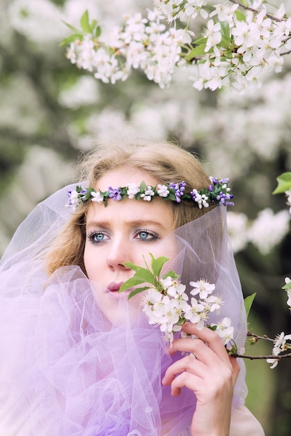 bela jovem loira na coroa de flores florescendo árvores na primavera