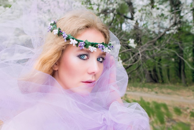 bela jovem loira na coroa de flores florescendo árvores na primavera