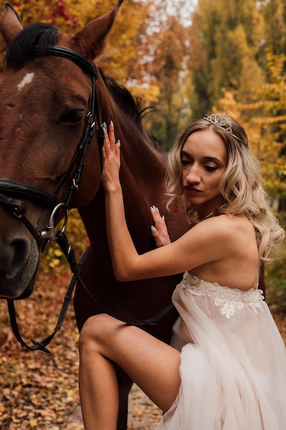 Bela jovem loira posando em um parque no outono com um cavalo