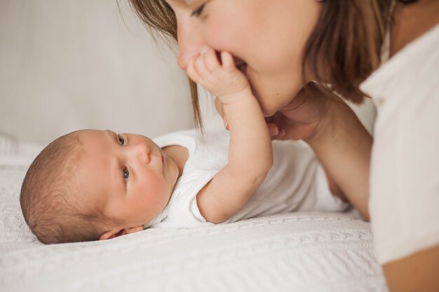 Bela jovem mãe brinca com o bebê na cama. Maternidade.