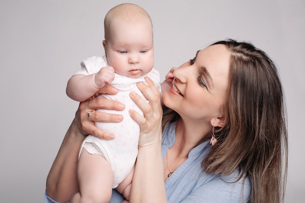 Bela jovem mãe segura o filho nas mãos e parece feliz