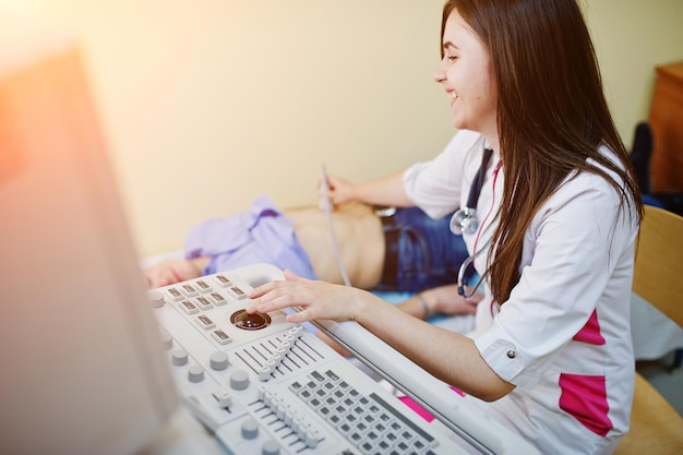 Bela jovem médica fazendo ultra-sonografia diagnóstica em um paciente