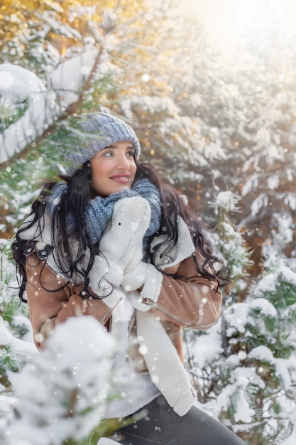 bela jovem na queda de neve na floresta no inverno