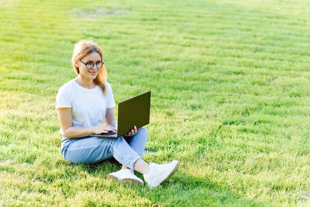 Bela jovem navegando na internet no laptop ao ar livre.