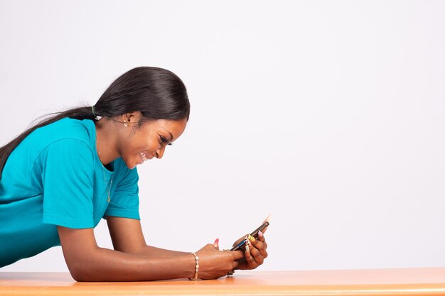 Bela jovem negra descansando em uma mesa e usando o telefone