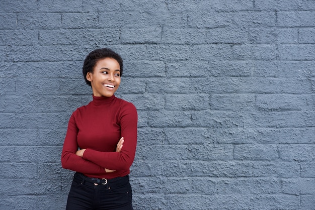 Bela jovem negra sorrindo contra parede cinza