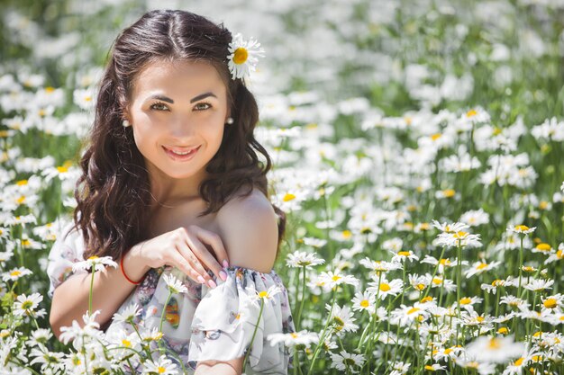 Bela jovem no campo de camomila. Linda menina com flores