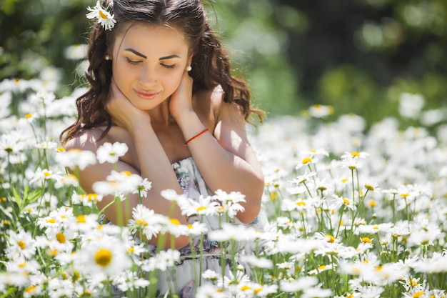 Bela jovem no campo de camomila. Linda menina com flores