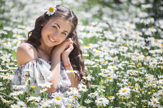 Bela jovem no campo de camomila. Linda menina com flores