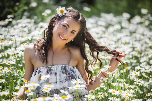 Bela jovem no campo de camomila. Linda menina com flores