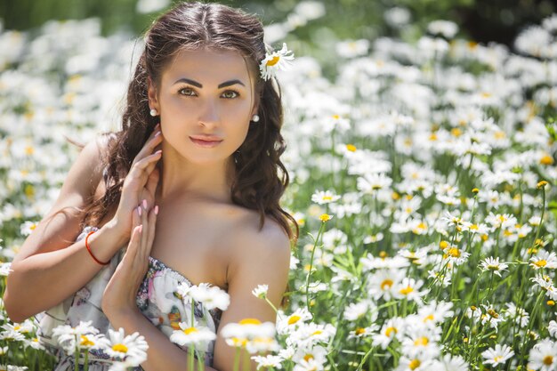 Bela jovem no campo de camomila. Linda menina com flores