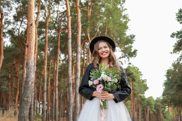 Bela jovem noiva com buquê de flores no dia do casamento ao ar livre