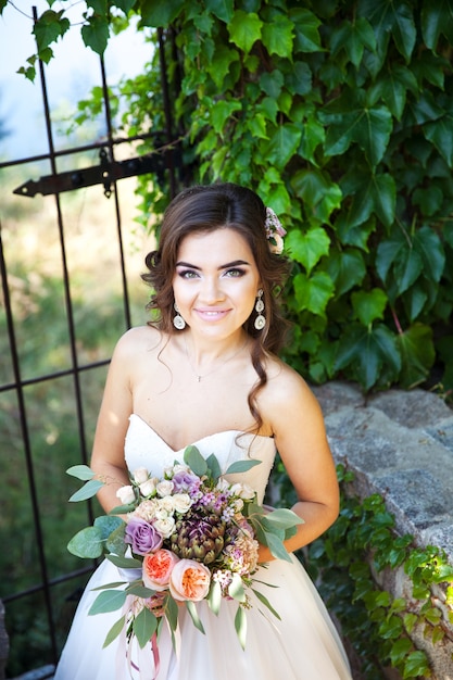 Bela jovem noiva com um buquê de flores do casamento.