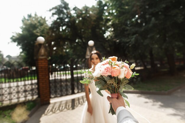 Foto bela jovem noiva elegante vestido branco, sorrindo encontra seu noivo no parque