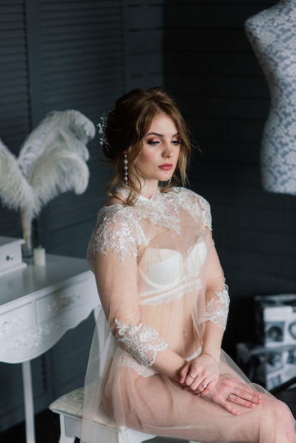 Bela jovem noiva em lingerie branca como preparativos para o casamento