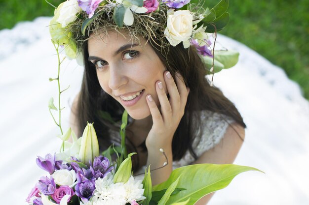 Bela jovem noiva em uma coroa de flores com um buquê na mão