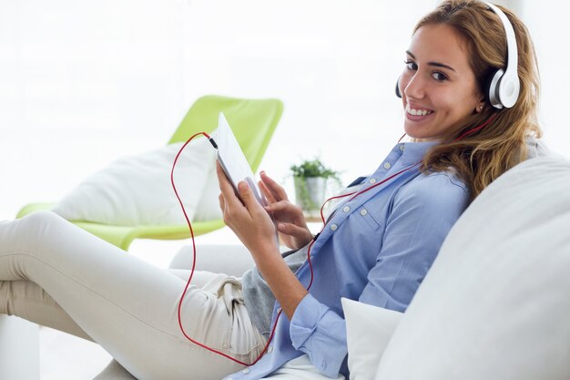 Foto bela jovem ouvindo música com tablet digital em