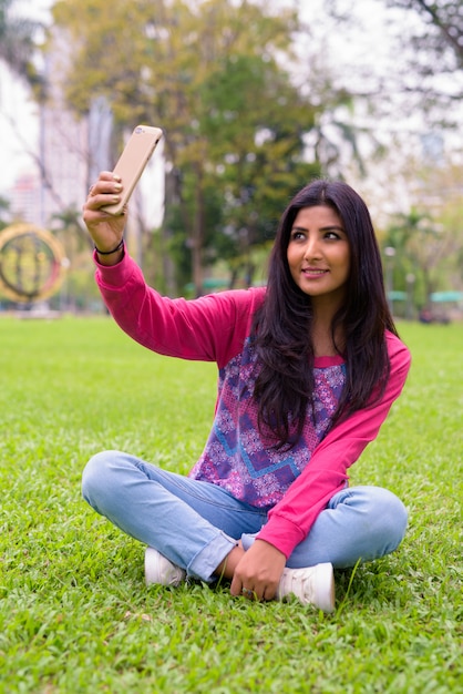 Bela jovem persa feliz tirando uma selfie no parque