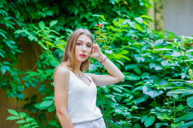 Bela jovem posando ao ar livre, usando um vestido branco elegante. Estilo de verão.