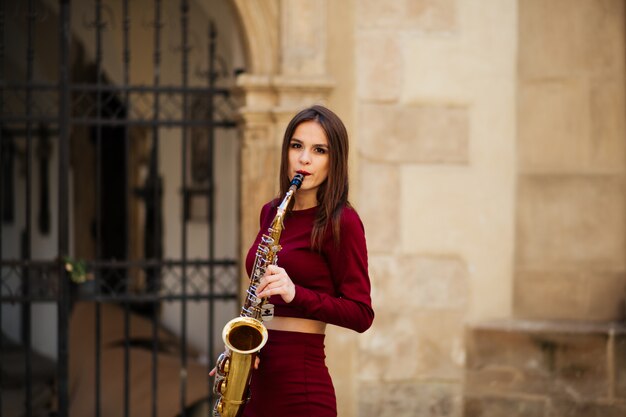 Bela jovem posando nas ruas da cidade com seu saxofone