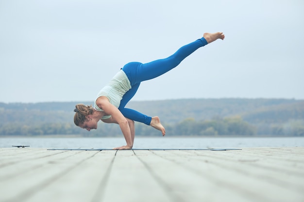 Bela jovem pratica ioga asana Eka Pada Bakasana