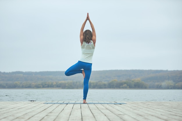 Bela jovem pratica yoga asana Parshva Vrikshasana