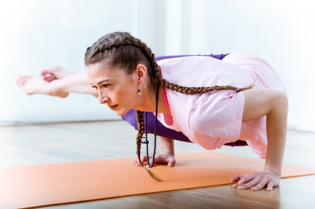 Foto bela jovem praticando yoga em casa.