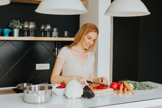 Bela jovem preparando uma refeição saudável na cozinha