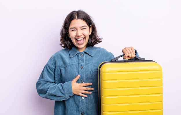 Bela jovem rindo alto de alguma piada hilária. conceito de mala de viagem