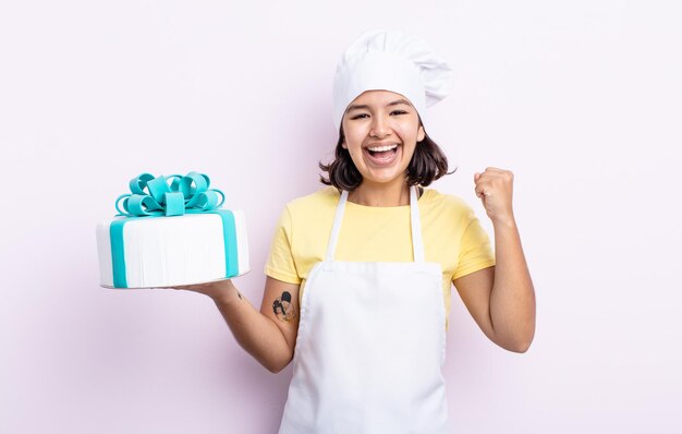 Bela jovem se sentindo chocada, rindo e comemorando o sucesso. chef cozinhando um bolo